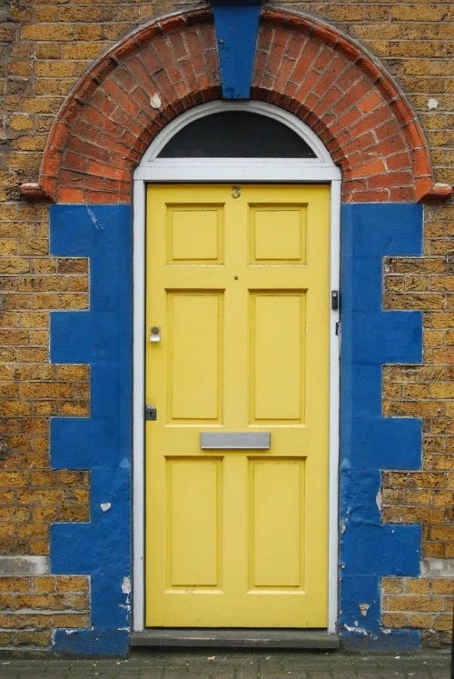 gelbes haustür design originell blau ziegelmauer