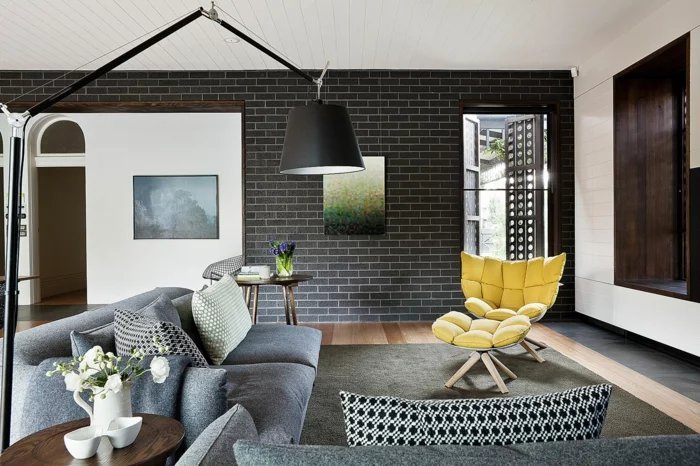wände gestalten wohnzimmer dunkle wandfliesen gelber sessel graues sofa