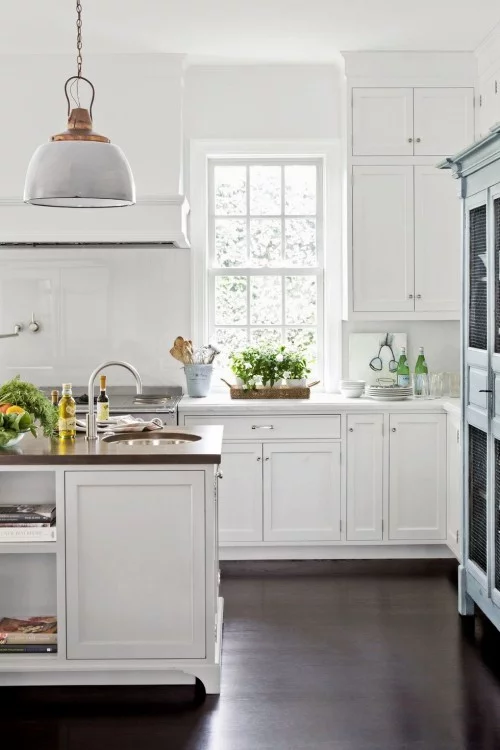 Gemütliche Küche ganz in weiß visueller Kontrast dunkler Holzboden grüne Akzente