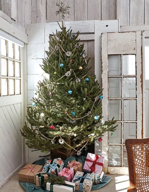 Weihnachten auf dem Lande feiern Christbaum in der Ecke schön geschmückt darunter Geschenk