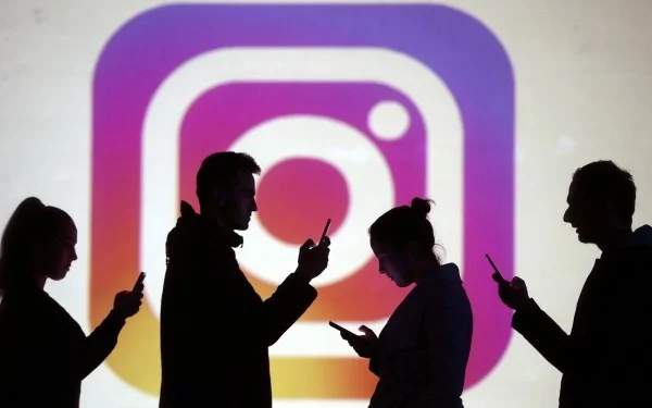 Image: Silhouettes of mobile users are seen next to a screen projection of Instagram logo in this picture illustration