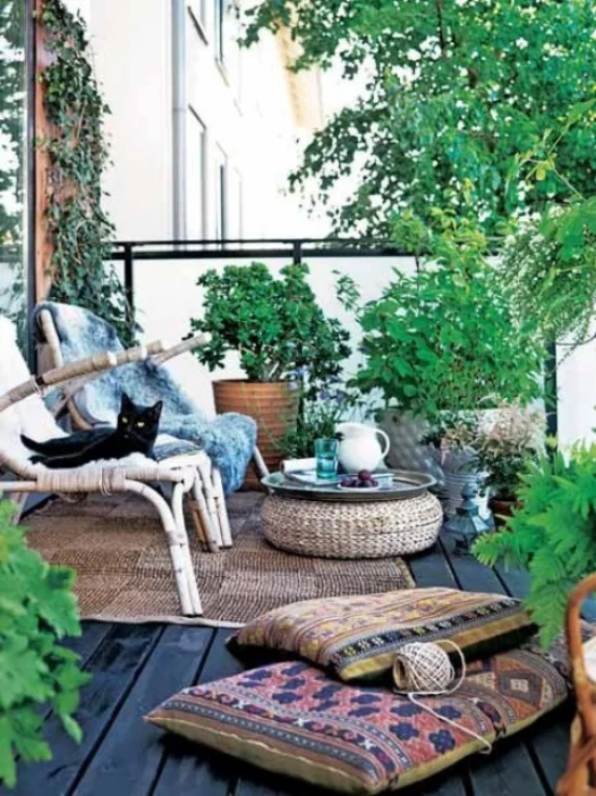 Holzterrasse gestalten Boho Style Sitzkissen schwarzer Kater viele grüne Pflanzen