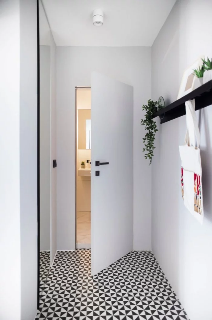 Kleines Apartment einrichten Flur ganz in weiß gestaltet kleine Akzente in Schwarz Regal