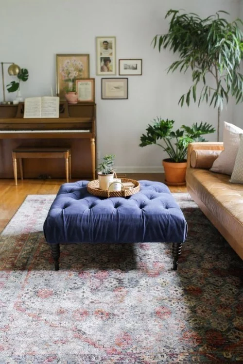 Asymmetrie im Interieur Wohnzimmer Teppich Sofa Zimmerpflanzen blauer Hocker mit Liebe zum Detail eingerichtet