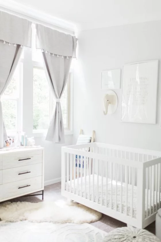 Babyzimmer in Weiß Kinderbett Kommode Gardinen viel Licht Fell auf dem Boden