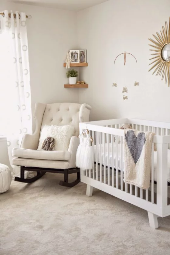Babyzimmer in Weiß bequemer Sessel Babybett weiche Kissen Wurfdecken Wanddeko