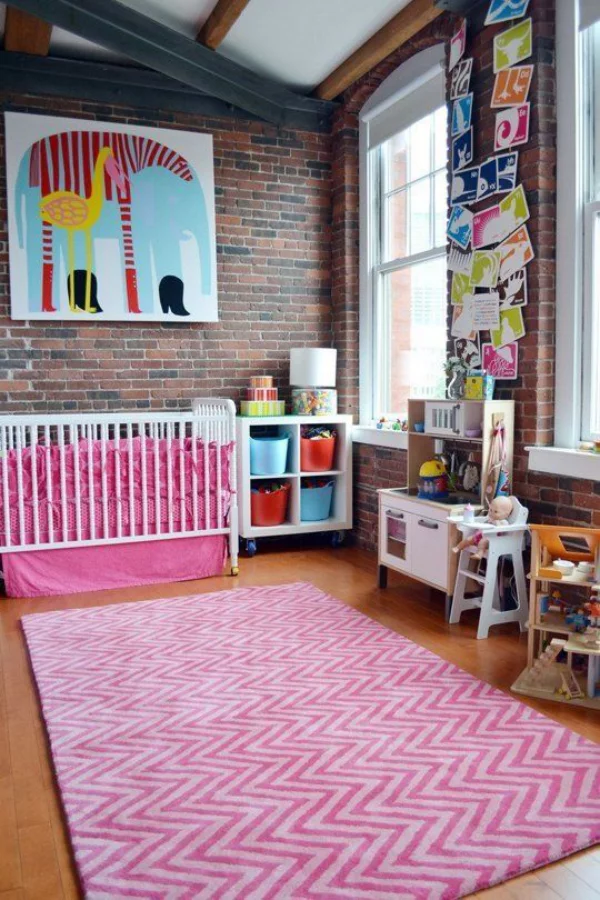 Kunterbuntes Babyzimmer Ziegelwand als Akzent rosa Teppich Bettwäsche Bilder Zeichnungen als Wanddekoration