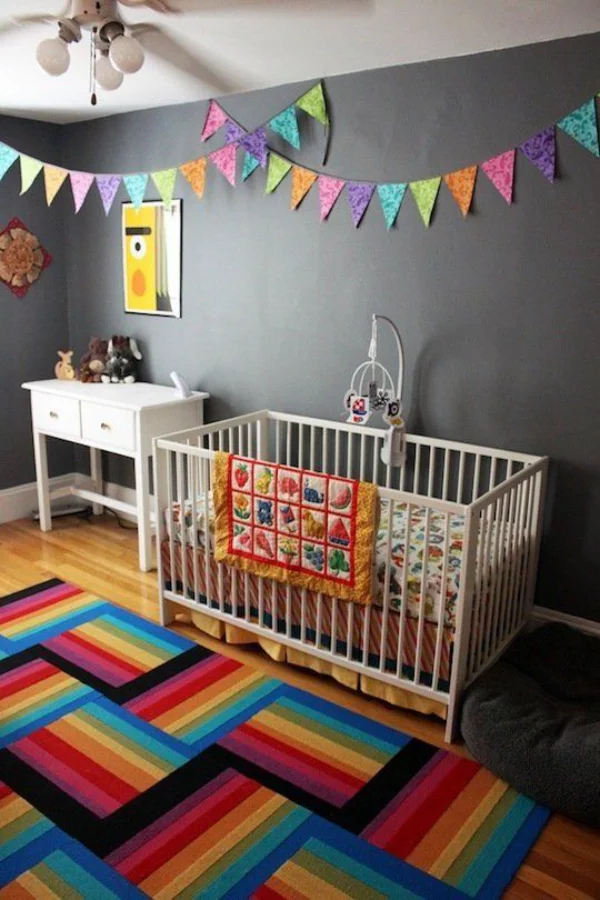 Kunterbuntes Babyzimmer dunkelgraue Wand aufpeppen bunte Girlanden farbenfroher Teppich