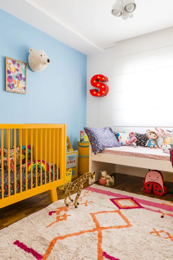 Kunterbuntes Babyzimmer gelbes Kinderbett blaue Wand weiße Wand weicher Teppich Wanddekoration Buchstabe